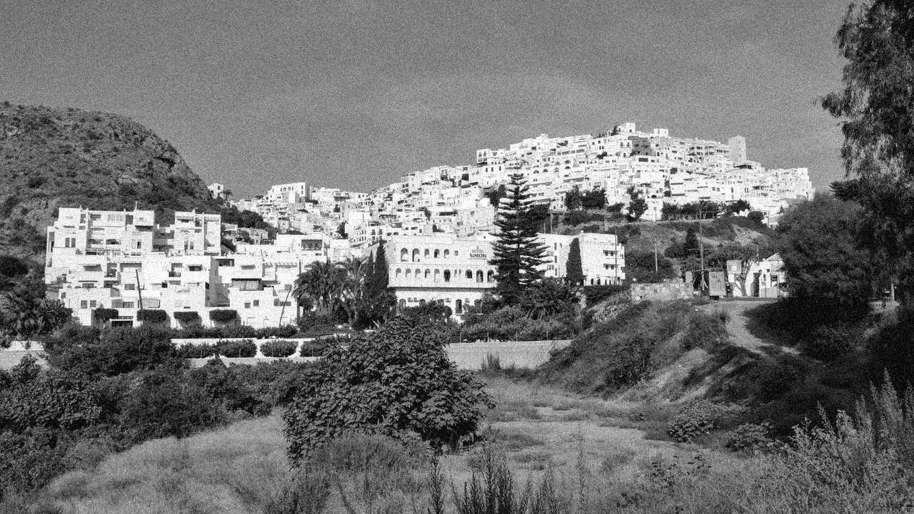 The old village of Mojácar rising white across the hillside, seen from the dry riverbed below.